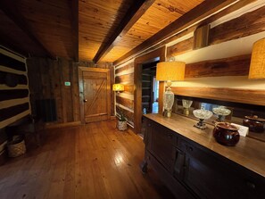A wooden interior with a wooden door, a lamp, and a mirror on a dresser.