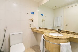 A bathroom with a toilet, a sink, a mirror, and a shower. - Suite w/ Pool View in Luxury Resort Jurere Jbv348 (Florianópolis)