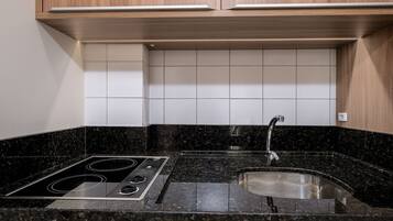 A kitchen with a black granite countertop, stainless steel sink, and a built-in stove.