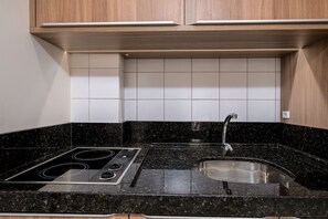 A kitchen with a black granite countertop, stainless steel sink, and a built-in stove. - Spectacular Suite in a Luxurious Resort Jbv179 (Florianópolis)
