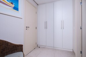A room with a white wardrobe, a wicker chair, and a framed picture on the wall. - Spectacular Suite in a Luxurious Resort Jbv179 (Florianópolis)