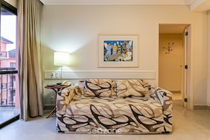 A living room with a sofa, a lamp, a painting, and a view of the outside. - Luxurious Suite in Beachfront Resort Jbv328 (Florianópolis)