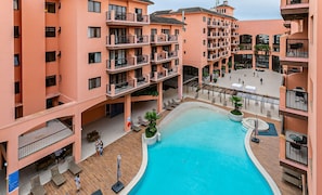 A multi-story hotel with a central swimming pool, outdoor seating, and balconies. - Luxurious Suite in Beachfront Resort Jbv328 (Florianópolis)