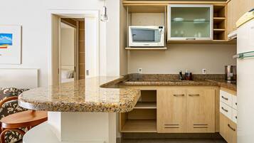 Eine Küche mit einer Granitabdeckung, Holzausstattung, einer Mikrowelle und einem Kühlschrank.