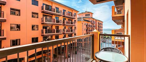 A multi-story building with balconies, a glass table, and chairs on the balcony.