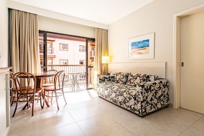 A living room with a sofa, dining table, chairs, a balcony with curtains, and a painting on the wall. - Suite W/beautiful View in Resort in Jurere Jbv252 (Florianópolis)