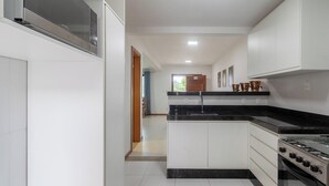 A modern kitchen with white cabinetry, a black countertop, and a gas stove.