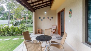 A covered patio with wicker chairs, a small table, and decorative plates on the wall.