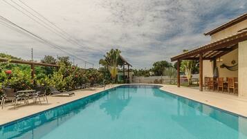 A swimming pool with lounge chairs and a covered seating area.