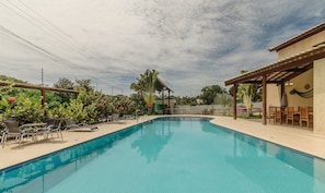 A swimming pool with lounge chairs and a covered seating area.