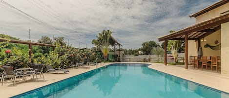 A swimming pool with lounge chairs and a covered seating area.