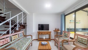 A living room with a TV, wooden furniture, a staircase, and a view of the outside. - House in Cond. W/pool, 500 m From the Sea Atp0001 (Porto Seguro)