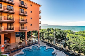 Un hotel amb piscina, zones d'estar a l'exterior i vistes al mar.
