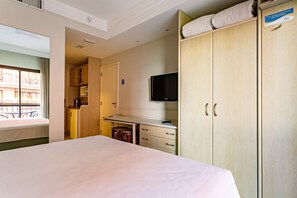 A hotel room with a bed, a desk with a chair, a television, and a wardrobe. - Studio in Spectacular Luxury Resort Jbv106 (Florianópolis)