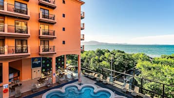 Ein Hotel mit Pool, Sitzgelegenheiten im Freien und Meerblick.