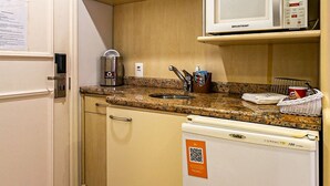 Una kitchenette compacta equipada con microondas, cafetera y refrigerador.