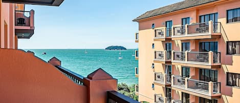 A multi-story building with balconies overlooking a body of water with boats.