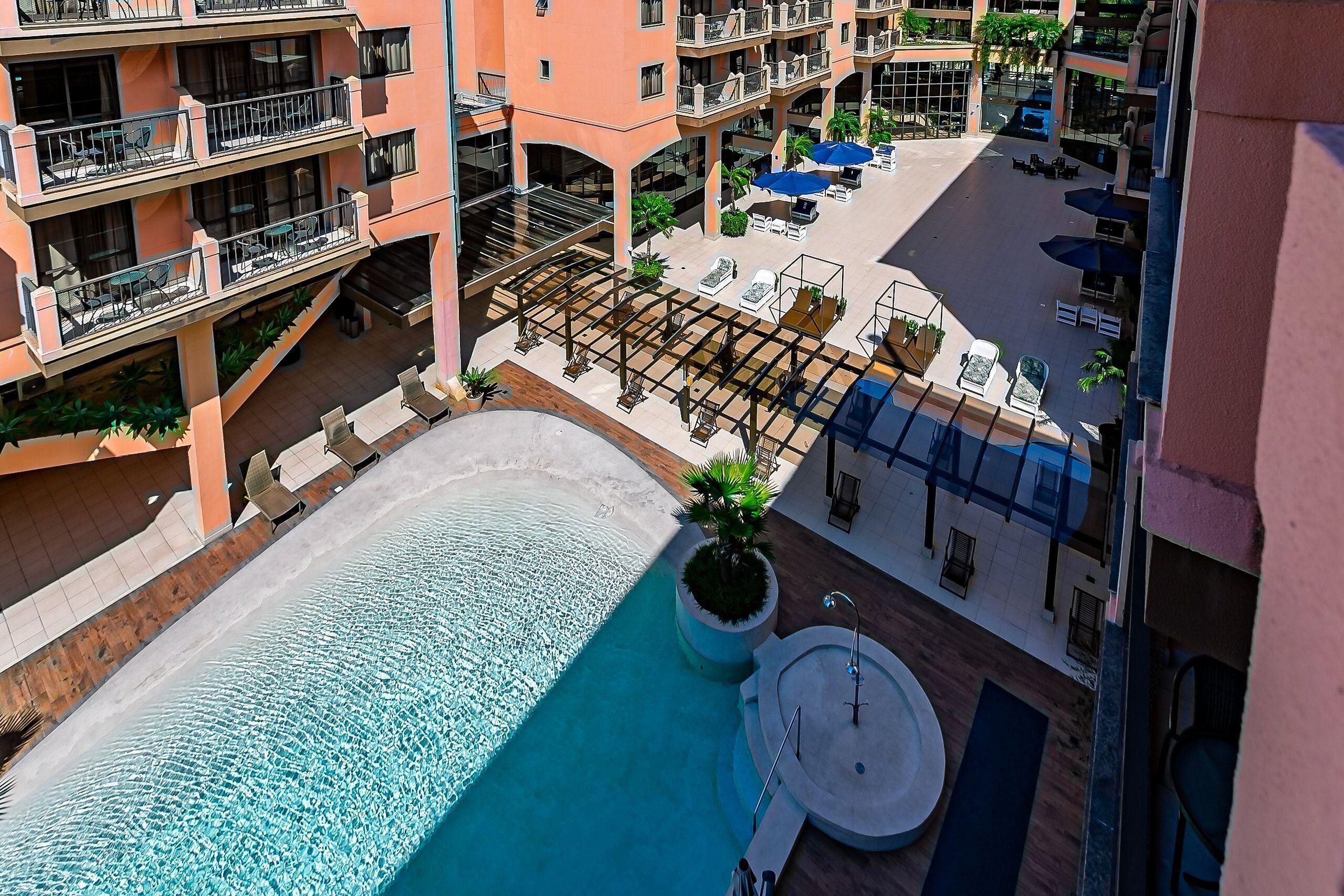 A rooftop pool area with a sun terrace, lounge chairs, and a jacuzzi.