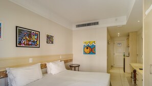 Ein Hotelzimmer mit einem Bett, einem Nachttisch, einem kleinen runden Tisch und Kunstwerken an den Wänden.