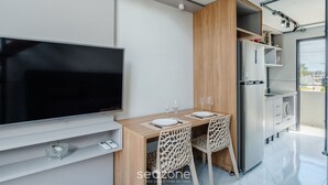 Una cocina moderna con televisor de pantalla plana, armarios de madera y refrigerador.