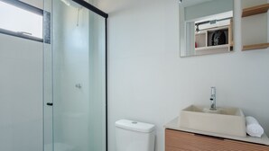 Un baño moderno con cabina de ducha de vidrio, lavamanos blanco y tocador de madera.