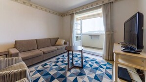 Een kamer met een bank, een kleine ronde tafel, een televisie en een kamer met een patroon.