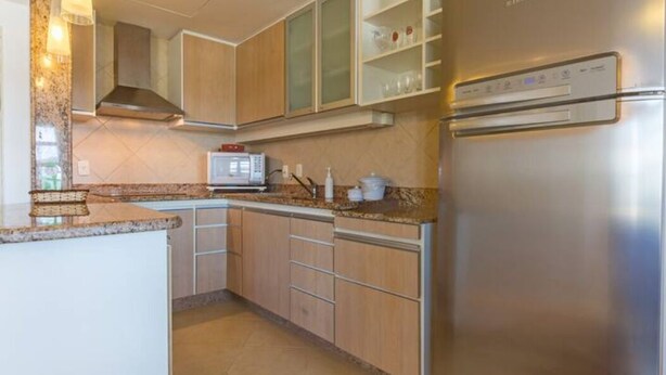 Een moderne keuken met roestvrijstalen apparatuur, houten kastjes en een inbouwmagnetron.