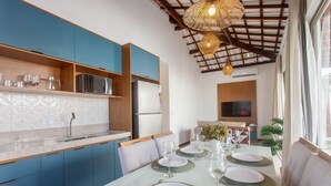 Une cuisine moderne avec des meubles bleus, un plan de travail blanc et un coin repas aménagé pour quatre personnes, avec une table en verre.