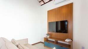 Un salon moderne avec un meuble de rangement en bois pour l’équipement audiovisuel, un téléviseur à écran plat et un canapé beige.