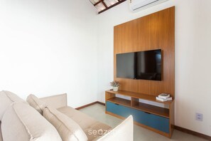 A modern living room with a wooden entertainment unit, a flat-screen TV, and a beige sofa. - 2-suite House by the Lagoon in Marau Cdl0008 (Maraú)