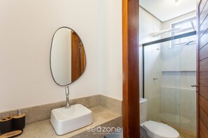 Un baño con lavamanos blanco, espejo y cabina de ducha de vidrio.