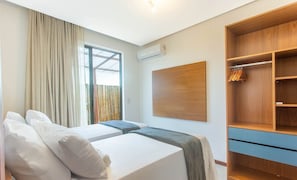 Un dormitorio con cama, armario y ventana con cortinas.