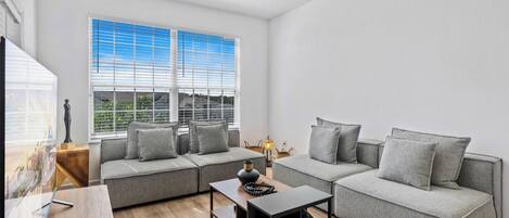 Ein modernes Wohnzimmer mit einer Eckcouch, einem Couchtisch und einem Deckenventilator.