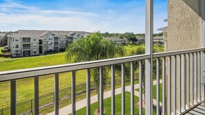 A residential building with a balcony overlooking a well-maintained lawn and neighboring houses. - Beautiful Condo at Windsor Palms Resort (Kissimmee)