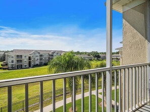 A residential building with a balcony overlooking a well-maintained lawn and neighboring houses. - Beautiful Condo at Windsor Palms Resort (Kissimmee)