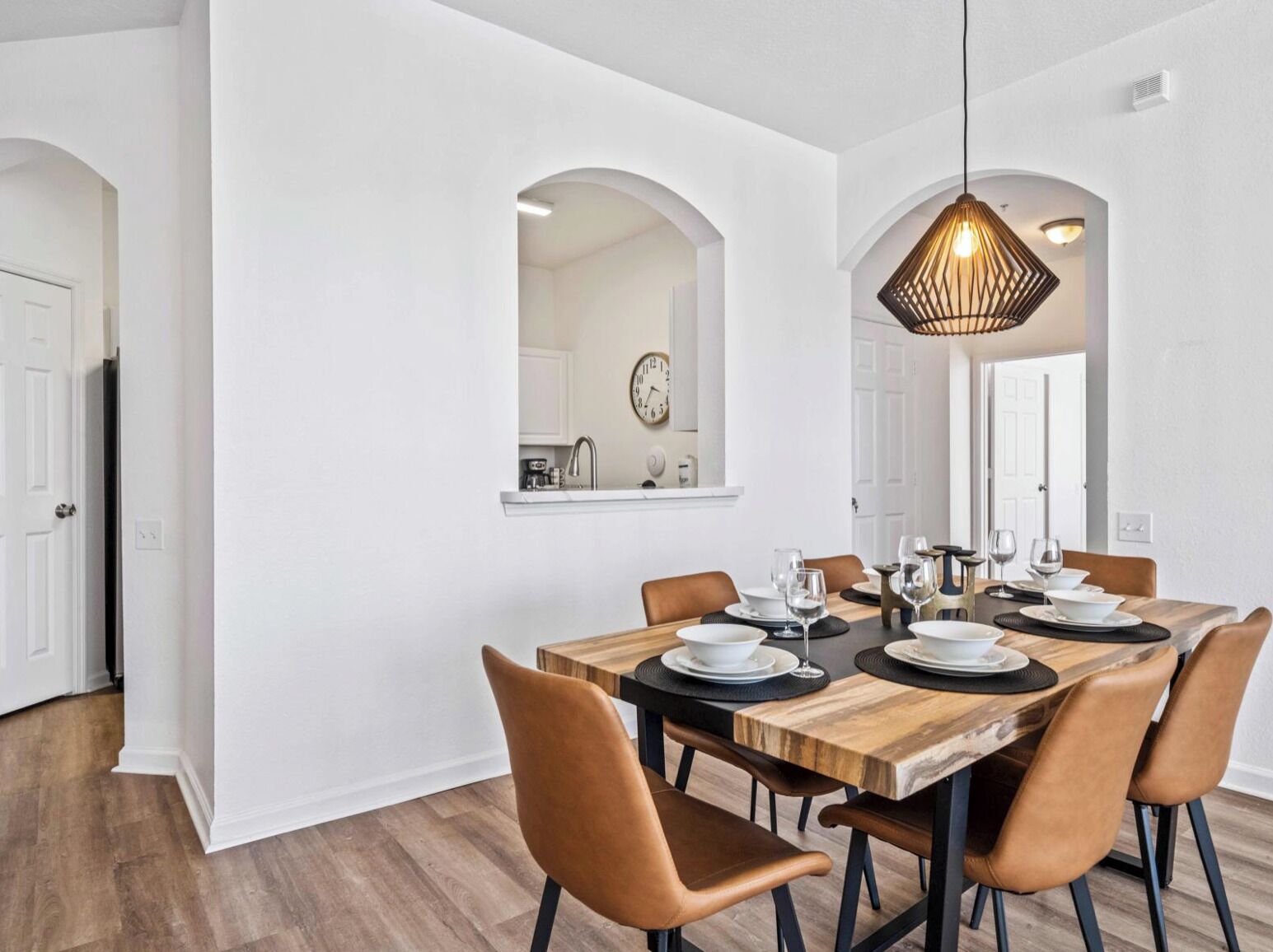 Un coin repas avec une table en bois dressée pour six personnes, entourée de six chaises.