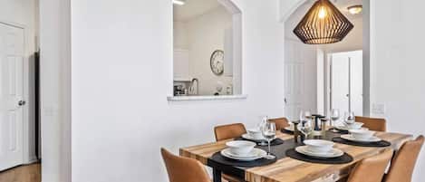 Un coin repas avec une table en bois dressée pour six personnes, entourée de six chaises.