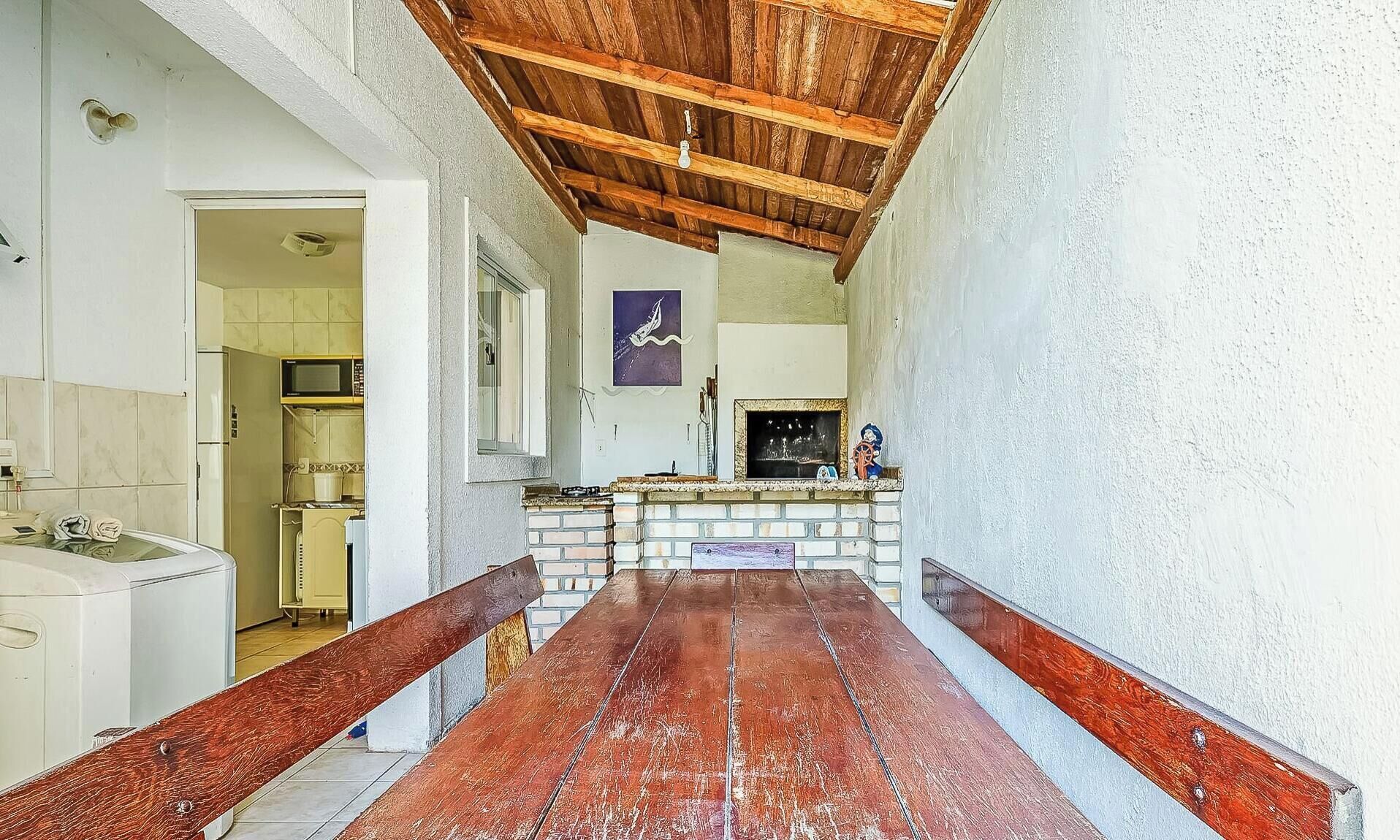 Un pasillo estrecho con un banco de madera, una chimenea de ladrillo y una zona de cocina con un microondas.