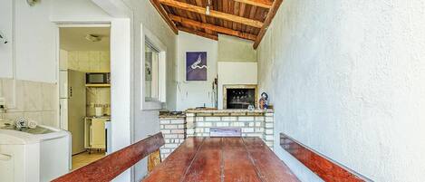 Un pasillo estrecho con un banco de madera, una chimenea de ladrillo y una zona de cocina con un microondas.