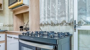 A kitchen with a stove, cabinets, and a patterned wall. - House With Pool in Cond 150m Beach Mariscal Ccm004 (Bombinhas)