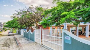 A gated residential area with a paved road, parked cars, and a building with a blue and white facade. - House With Pool in Cond 150m Beach Mariscal Ccm004 (Bombinhas)