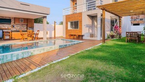 Ein modernes Haus mit Swimmingpool, Sitzgelegenheit im Freien und einer überdachten Terrasse.