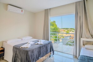 A hotel room with a bed, a window with curtains, a balcony, and an air conditioning unit. - Duplex House With Pool in Jacuipe/ba Pqa0011 (Camaçari)