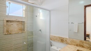 Ein modernes Badezimmer mit einer Duschkabine aus Glas, einem Marmorwaschtisch und einem großen Spiegel.