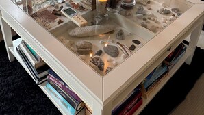 Un tavolino in vetro con candele, un telecomando e oggetti decorativi.