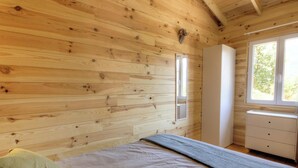 Una habitación con paneles de madera, una cama, un aparador y una ventana.