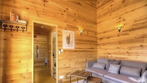 Un interior de madera con un sofá, un cuadro enmarcado y un perchero.