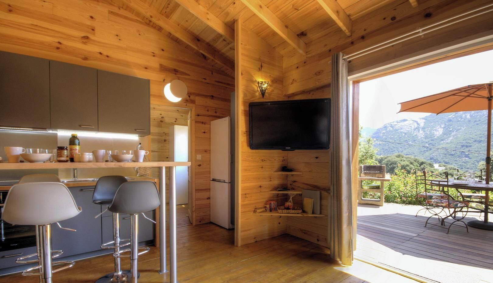 A wooden interior with a kitchen, bar area, and a TV.