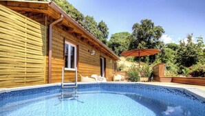 Una cabaña de madera con piscina, mobiliario de exterior y zona de patio.