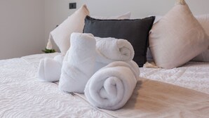 A neatly made bed with rolled white towels, a dark gray pillow, and a light gray pillow. - Beautiful Apt in Las Condes with Pool (Las Condes)
